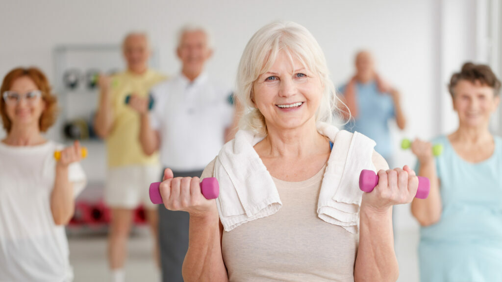 Active happy elders with colorful dumbbells during training